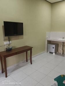 sala de estar con TV de pantalla plana en la pared en ALZA BUDGET ROOMStay en Pantai Cenang