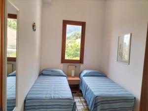 two beds in a room with a mirror and a window at Villa Rizzo in Castellammare del Golfo