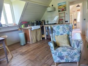 a living room with a chair and a kitchen at Lodge De Zandbalk in Sebaldeburen