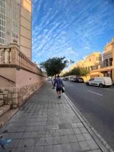 Un homme marchant sur un trottoir dans une rue de la ville dans l'établissement SANTA BARBARA APARTAMENTO, à Alicante