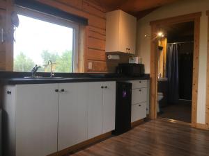 a kitchen with white cabinets and a sink and a window at Oma's and Opa's Northern Lights Viewing Cabin in Whitehorse