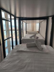 two twin beds in a room with windows at Saranda Boutique Hostel in Sarandë