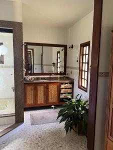 a bathroom with a sink and a large mirror at Chácara das Lendas e Canções in Passa Quatro