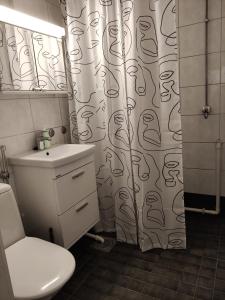 a bathroom with a toilet and a shower curtain at Yyterin portti in Pori