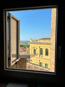 a window with a view of a yellow building at Casa Robin in Montemarciano