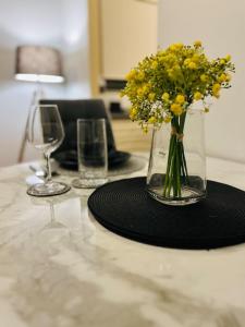a table with a vase of flowers and two glasses at Cozy Luxurious Apartment in Edgware