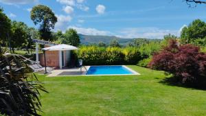 a swimming pool in a garden with an umbrella at Casa do Cerrado in Agunchos