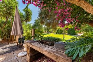 un jardín con una mesa de madera y una sombrilla en Villa - Algarve, Portugal, 4 Bed ensuite, private pool, lake and beautiful gardens en Almancil