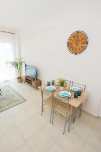 a dining room with a table and a clock on the wall at Make yourself at home! MYSTH in Nea Fokea