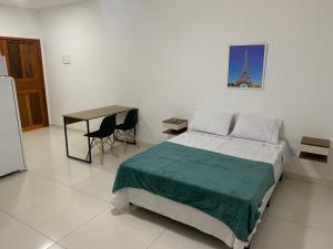 1 dormitorio con 1 cama, mesa y nevera en Loft PARIS para Casais, em Iguaba Grande, 150 metros da praia en Iguaba Grande