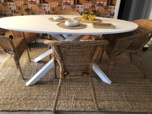 una mesa de comedor blanca con sillas de mimbre en Casa ESTELLA, en Magliolo