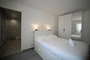 um quarto branco com uma cama e um espelho em Les cerisiers un petit coin de paradis pour deux proche du lac! em Sévrier