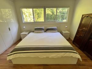 a bedroom with a large bed with two windows at Stunning Modern Beach House with Swimming Pool and Spectacular Sunsets in Tiny