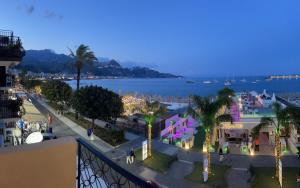 a view of a city at night with the ocean at La Finestra sul Mare Modern Apartment in Giardini Naxos