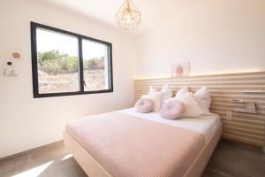 a bedroom with a bed with pillows and a window at Villa-soleil-levant vue mer panoramique in Sari Solenzara