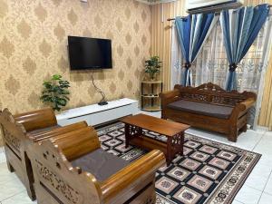 uma sala de estar com 2 sofás e uma televisão de ecrã plano em Homestay Jati by NazTi em Seremban