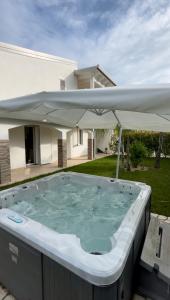 a hot tub with an umbrella in front of a house at TOT apartment in Policoro