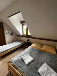 a attic bedroom with two beds and a window at Śnieżnicki Domek - Masyw Śnieżnika, Sudety in Stronie Śląskie