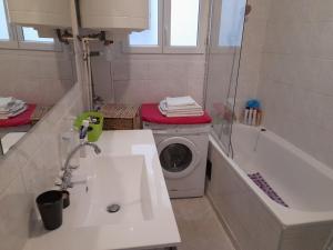 ein Badezimmer mit einer Waschmaschine neben einer Badewanne in der Unterkunft Havre de Paix 10 mn Centre Paris in Clichy