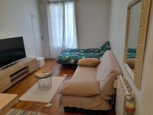 ein Wohnzimmer mit einem Sofa und einem TV in der Unterkunft Havre de Paix 10 mn Centre Paris in Clichy