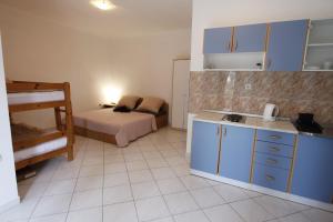 kuchnia z niebieskimi szafkami i łóżko w pokoju w obiekcie Apartmani Nika w Bibinje
