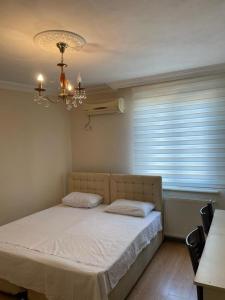ein Schlafzimmer mit einem Bett mit einem Kronleuchter und einem Fenster in der Unterkunft Kanarya Apart in Trabzon