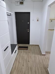 pasillo con puerta negra y suelo de madera en Apartament 2 camere en Zalău