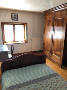 a bedroom with a bed and a wooden cabinet at Gîte de la Croix Mandet 