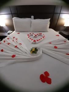 a white bed with red hearts and flowers on it at Hotel Maruá in São José dos Campos