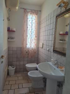 łazienka z umywalką, toaletą i lustrem w obiekcie Villa mara w mieście Specchiolla