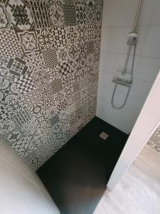 a bathroom with a shower with a patterned wall at Les Chambres d'Hotes chez Alisa et Daniel in Sarlat-la-Canéda