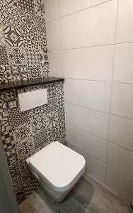 a white toilet in a bathroom with a tile wall at Les Chambres d'Hotes chez Alisa et Daniel in Sarlat-la-Canéda