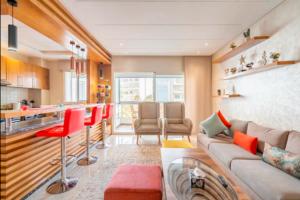 Appart 100 m2 haut standing en bord de mer في الدار البيضاء: غرفة معيشة مع أريكة وكراسي حمراء ومطبخ