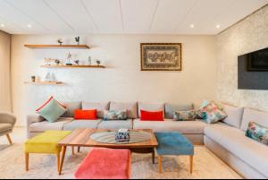 Appart 100 m2 haut standing en bord de mer في الدار البيضاء: غرفة معيشة مع أريكة مع وسائد ملونة