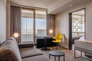 ein Wohnzimmer mit einem Sofa, einem Tisch und einem gelben Stuhl in der Unterkunft Four Points by Sheraton Munich Arabellapark in München