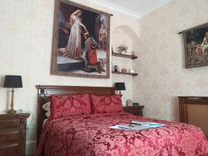 a bedroom with a red bed and a painting on the wall at St David's Guesthouse in Haverfordwest