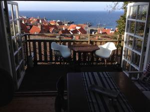 een balkon met een tafel en stoelen en de oceaan bij SPECTACULAR PANORAMIC VIEWS OF GUDHJEM in Gudhjem
