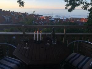 a table with wine glasses and candles on a balcony at SPECTACULAR PANORAMIC VIEWS OF GUDHJEM in Gudhjem