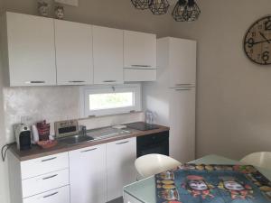 cocina con armarios blancos, mesa y fregadero en VILLA BORGHESE, en Racalmuto