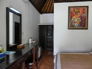 a bedroom with a desk with a mirror and a painting on the wall at Liberty Dive Resort in Tulamben