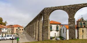 un vecchio ponte di pietra in una città con edifici di Casa dos Arcos a Vila do Conde