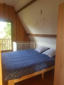 una camera da letto con un letto con lenzuola blu e una finestra di Maison du domaine de la petitière a Bonneville-la-Louvet