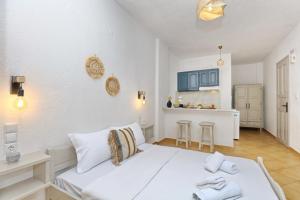 a bedroom with a white bed and a kitchen at Skopelos Panos Studios in Stafylos