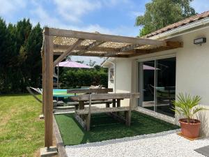 uma pérgola de madeira com uma mesa de piquenique num quintal em Agréable maison de vacances em Soustons