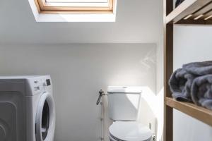 a bathroom with a washing machine and a toilet at Les Figuiers - Appartement de Standing avec 2 Chambres in Andenne