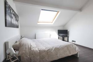 a white bedroom with a bed and a window at Les Figuiers - Appartement de Standing avec 2 Chambres in Andenne