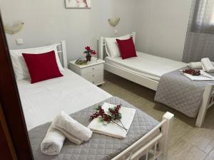 a bedroom with two beds with red and white pillows at Anthoula house in Vlachopoulátika