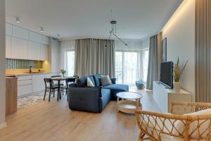 a living room with a blue couch and a kitchen at Downtown Apartments Nadmotławie Estate Gym, Sauna & Parking in Gdańsk