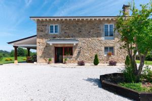 a stone house with a driveway in front of it at Villa Colasa, casa rústica con encanto en Selaya in Selaya