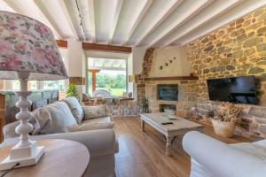 a living room with a couch and a stone wall at Villa Colasa, casa rústica con encanto en Selaya in Selaya